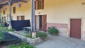 A rustic building with a stone wall, wooden door, and a covered outdoor seating area.