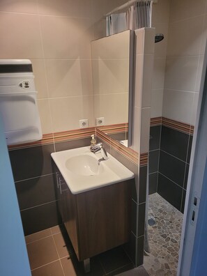 Ein Badezimmer mit einem weißen Waschbecken, einer Dusche und einem Spiegel.