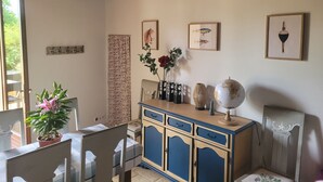 A room with a wooden ceiling, a dining table with chairs, a cabinet with drawers, and a globe on top.