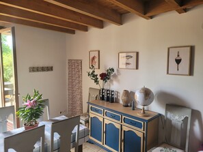 Ein Zimmer mit Holzboden, einem Esstisch mit Stühlen, einer Kommode und einem Globus darauf.