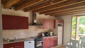 A kitchen with red cabinets, a dishwasher, a stove, and a microwave.
