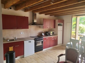 A kitchen with red cabinets, a dishwasher, a stove, and a microwave.