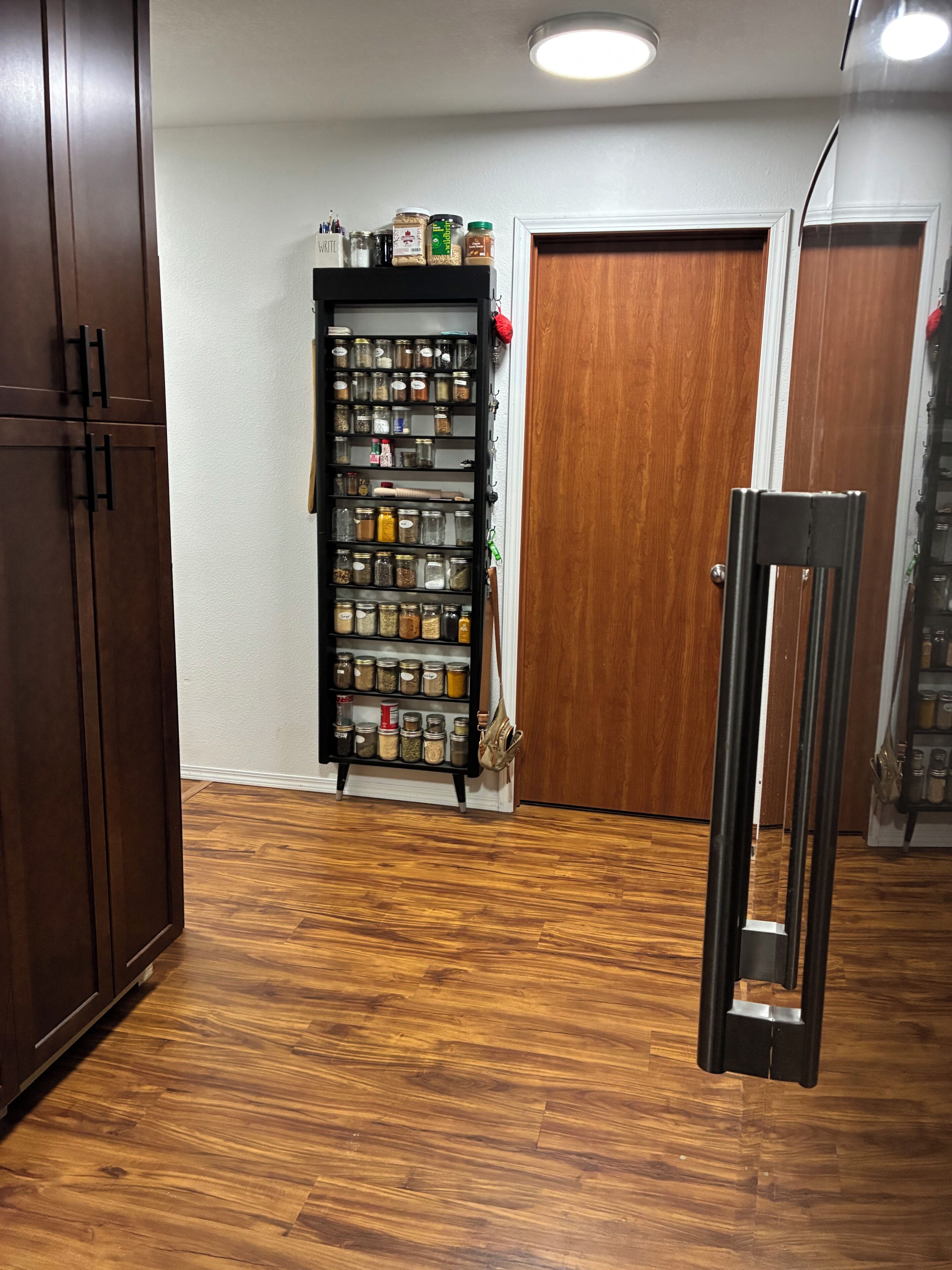 A kitchen with wooden cabinets, a spice rack, and a hanging rack.