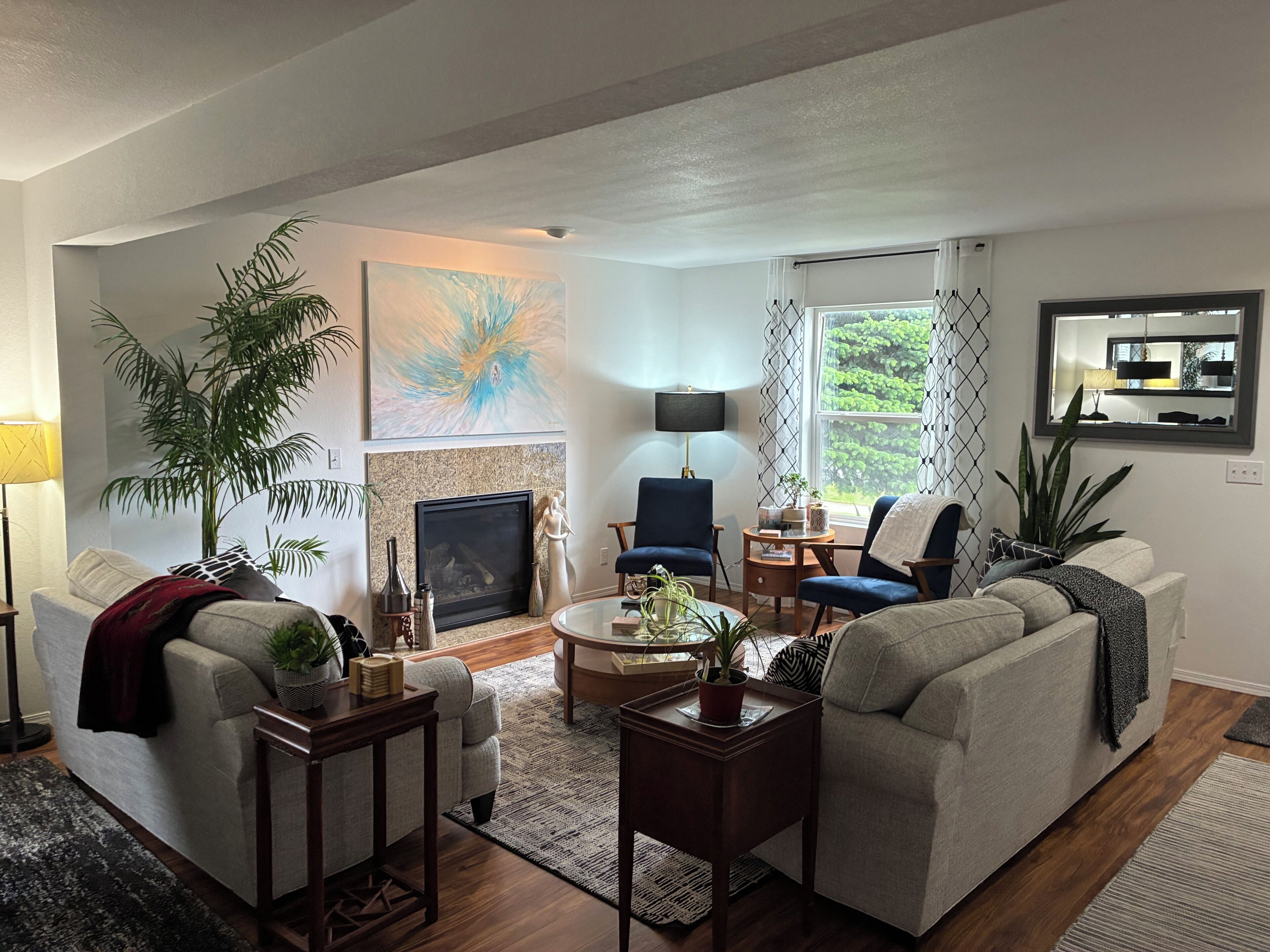 A living room with a fireplace, two armchairs, a sofa, a coffee table, and a TV mounted on the wall.