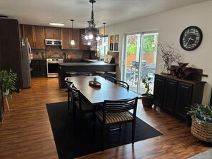 A modern kitchen with a central island, wooden cabinets, and a dining area with a large table and chairs.