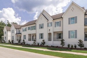 A row of white townhouses with multiple windows and balconies, a clear sky, and a well-maintained lawn. - The Oxford Escape | 3BR/3.5BA Near Ole Miss + M-Trade Park (Oxford)
