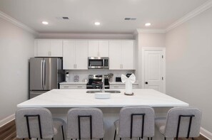 A modern kitchen with white cabinetry, stainless steel appliances, and a central island with seating. - The Oxford Escape | 3BR/3.5BA Near Ole Miss + M-Trade Park (Oxford)