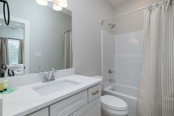A modern bathroom with a double sink, a toilet, and a shower.