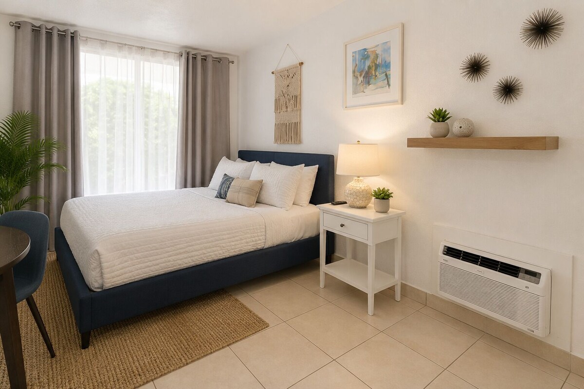 A bedroom with a bed, bedside table, lamp, wall decor, and a radiator.