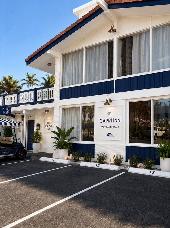 Un edificio de dos pisos con un cartel que dice 'The Capri Inn' y un estacionamiento al frente.