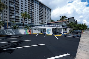 A hotel with a parking lot, a building with multiple floors, and a clear sky. - Beautiful Deluxe Queen Room (Fort Lauderdale)
