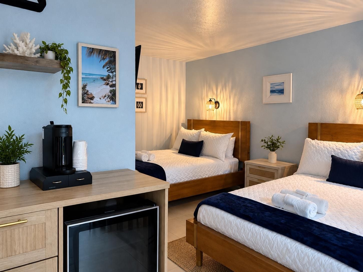 A hotel room with two beds, a desk, a coffee machine, and a TV.