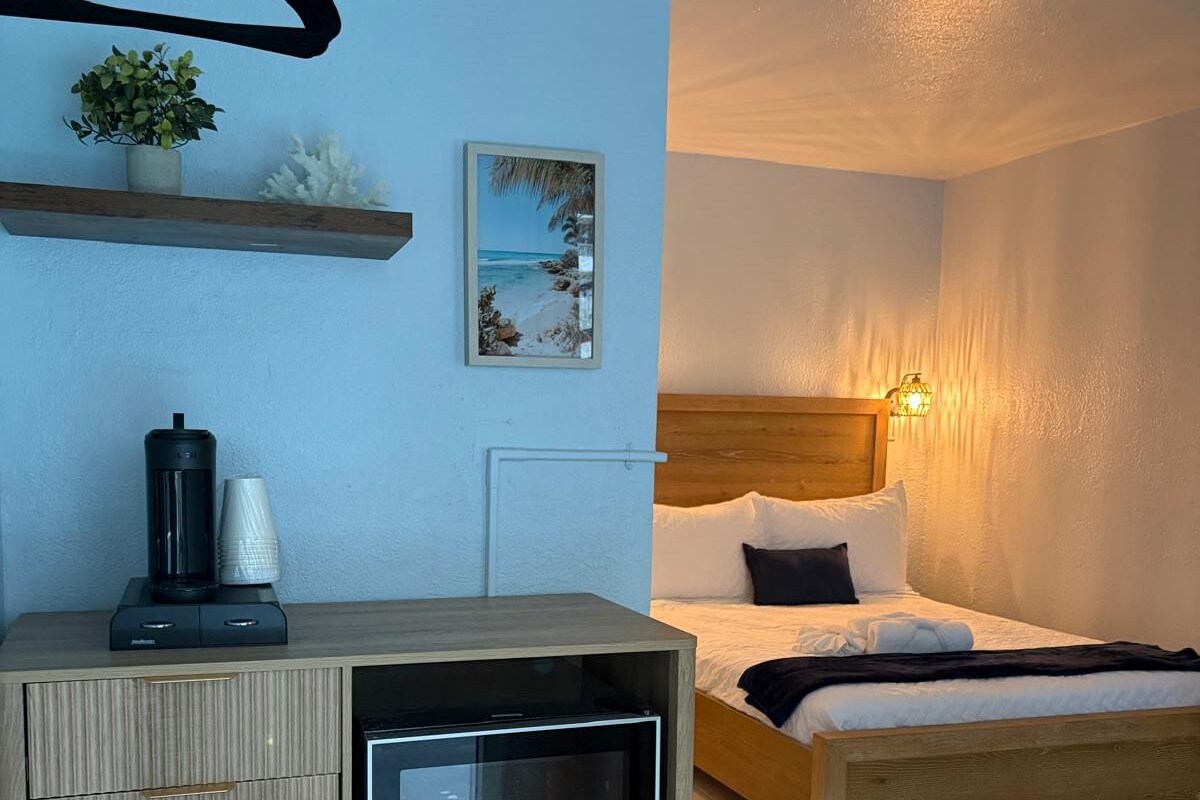 Un dormitorio con cama, mesita de noche y un pequeño refrigerador.