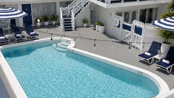 Un espace piscine avec des chaises longues, un escalier et un bâtiment doté de balcons.