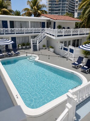 A pool area with lounge chairs, a staircase, and a building with balconies. - Beautiful Deluxe Queen Room (Fort Lauderdale)