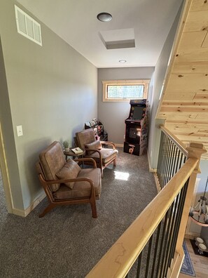 A living room with a wooden staircase, a fireplace, and a window. - Hayward Northwoods Escape -ATV Trails, Pond + Kayaks & Firepit (Hayward)