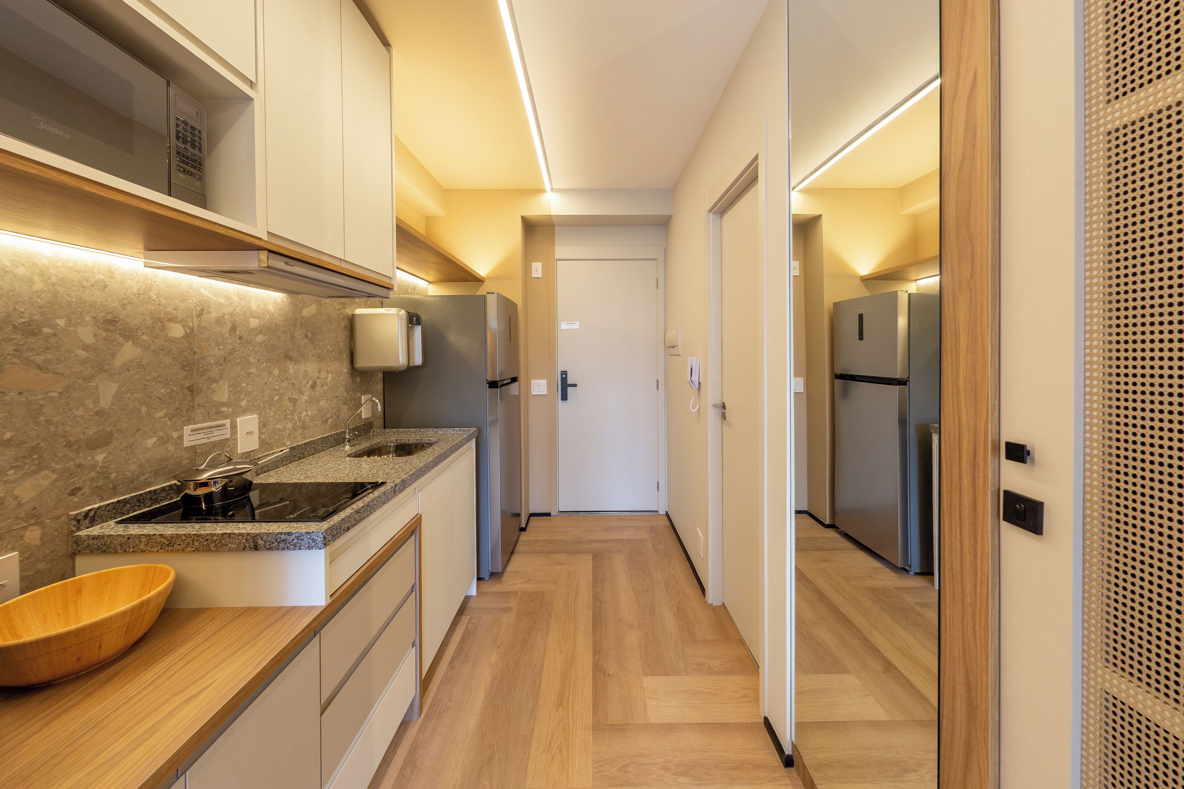Cozinha moderna com bancadas de granito, eletrodomésticos de aço inoxidável e piso de madeira.