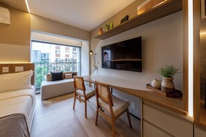 Quarto moderno com cama, escrivaninha e TV fixada na parede.