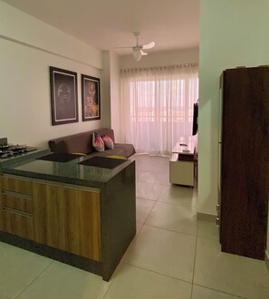 A modern kitchen with a central island, a dining area with a sofa, and a living room with a TV. - 2802 Unique Estudio Caragem (Belem)