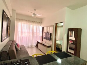 A living room with a sofa, a TV, a ceiling fan, and a dining area with a table and chairs. - 2802 Unique Estudio Caragem (Belem)