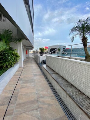 A corridor with tiled flooring, a white wall, and a palm tree. - 2802 Unique Estudio Caragem (Belem)
