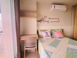 Une chambre à coucher comprenant un lit, un bureau, une chaise et un appareil de climatisation.