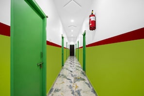 A corridor with green and red walls, a fire extinguisher mounted on the wall, and a patterned floor. - Classic Ramoji Film City (Hyderabad)