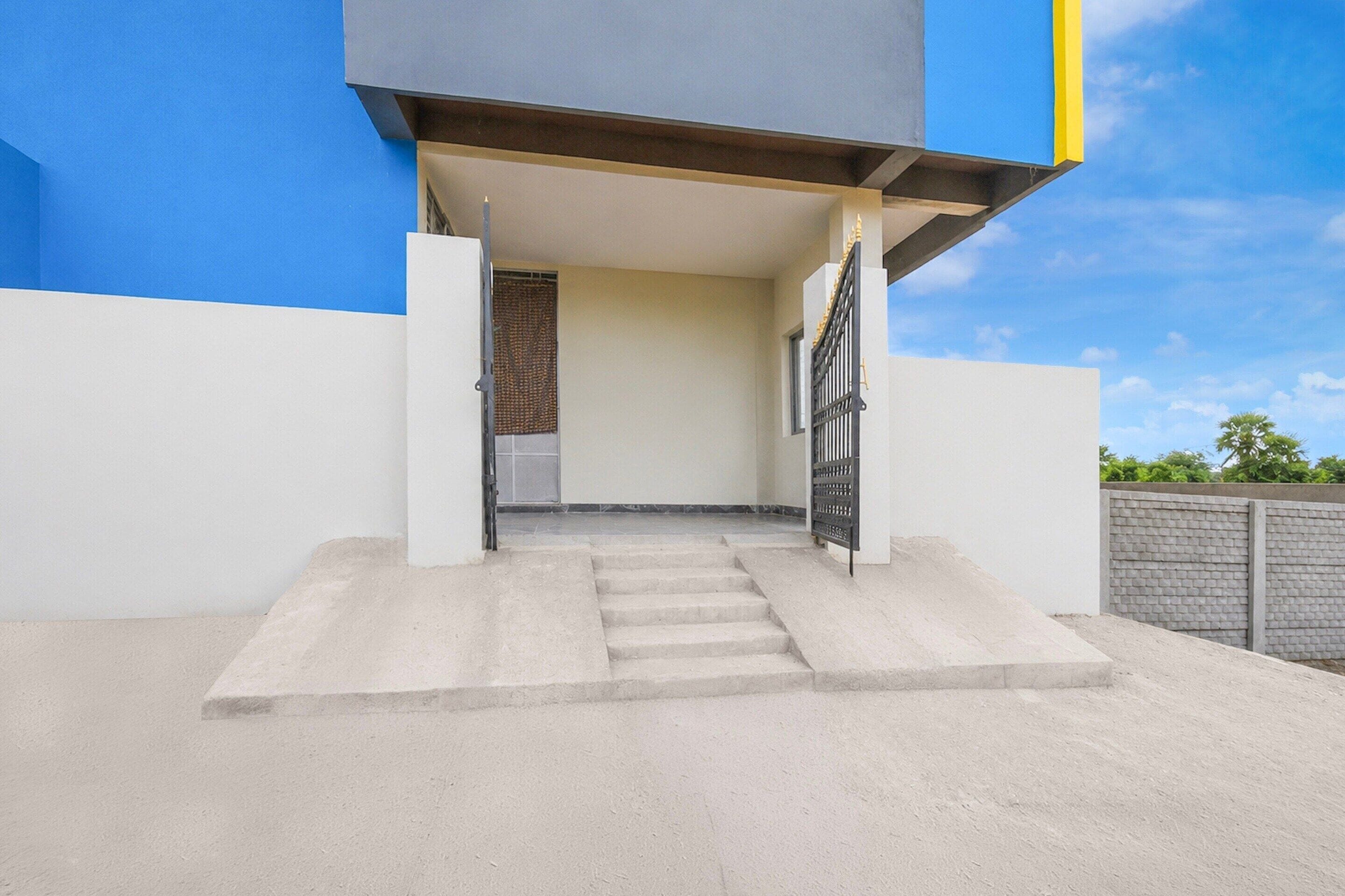 A modern building entrance with a concrete staircase leading to a door with a metal gate.