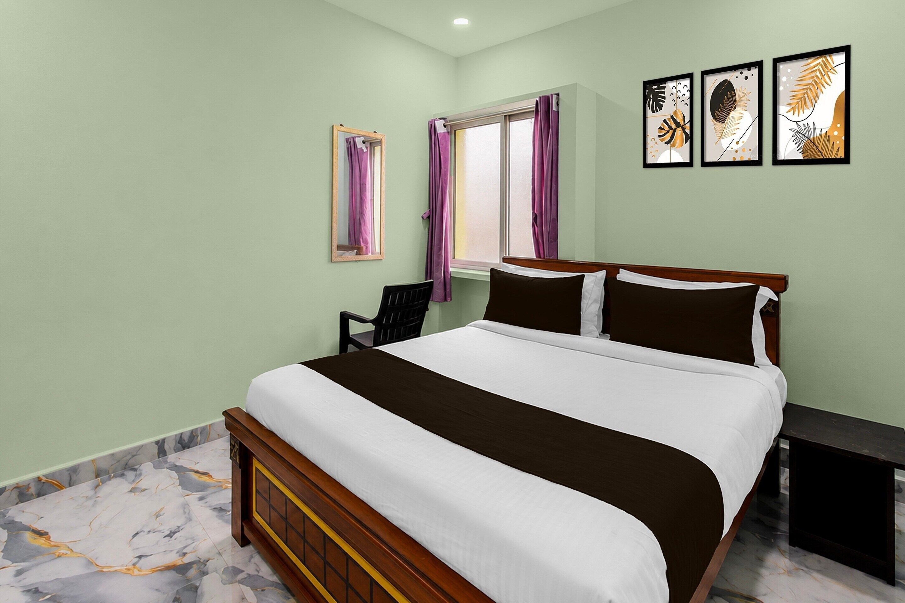 A bedroom with a bed, a chair, a window with curtains, and three framed pictures on the wall.