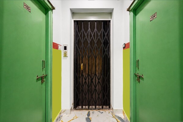 Un pasillo con dos puertas verdes, cada una con un número.