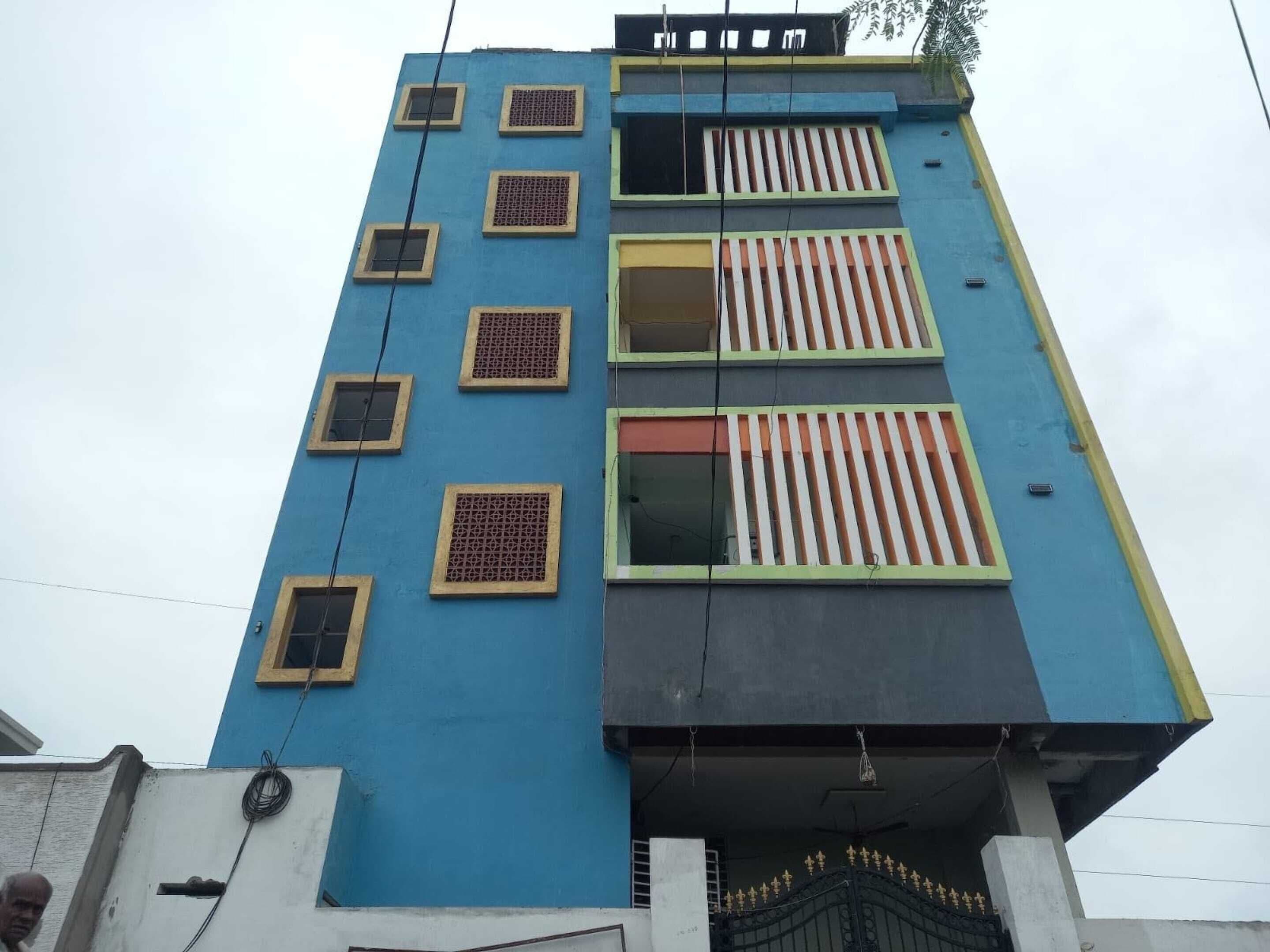 Ein mehrstöckiges Gebäude mit blauer Fassade, zahlreichen Fenstern mit verzierten Gittern und einem verschlossenen Eingang.