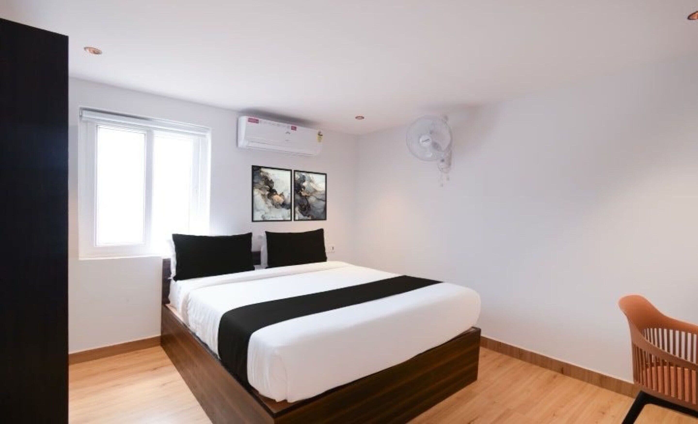 Un dormitorio con cama, ventana y aire acondicionado instalado en la pared.