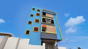 Edifício de hotel com fachada azul, várias janelas e uma placa indicando que é administrado pela OYO.
