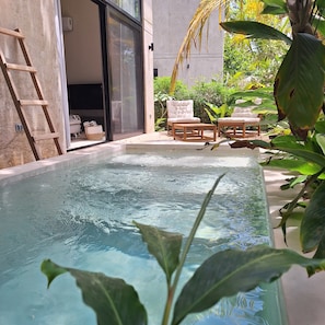 Piscina com deck de madeira e cadeiras de descanso.
