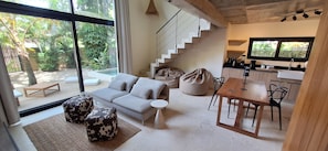 Decoração moderna com sofá, pufes, mesa de jantar e cozinha.