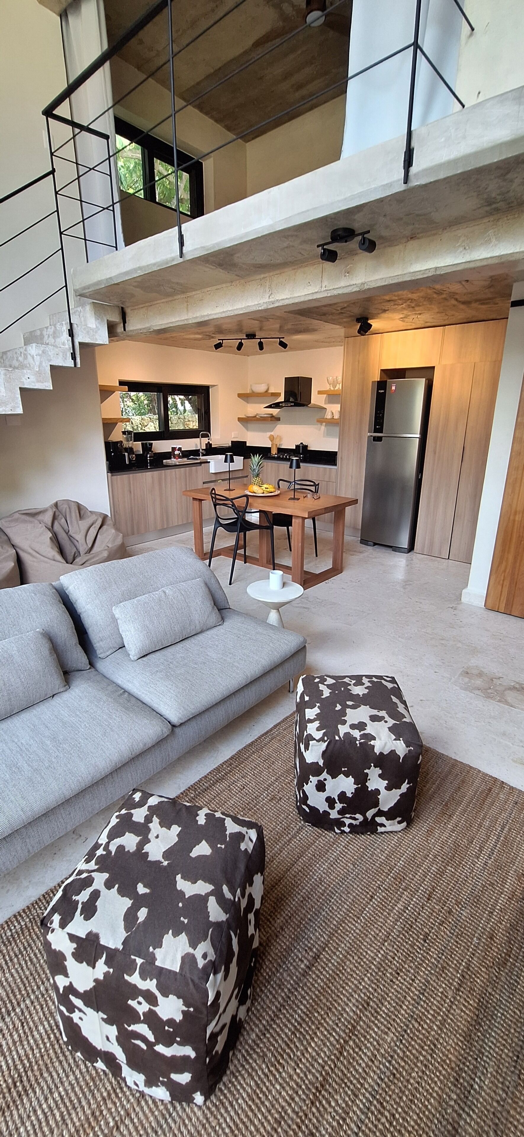 A modern living space with a sofa, ottomans, and a dining area with a table and chairs.