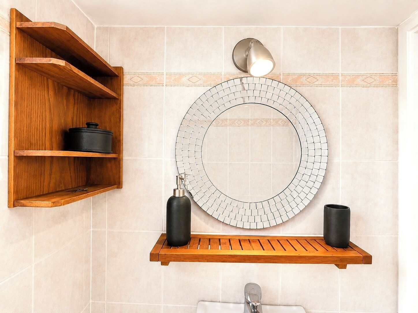 Een badkamer met een houten plank, een ronde spiegel en een wandlamp.