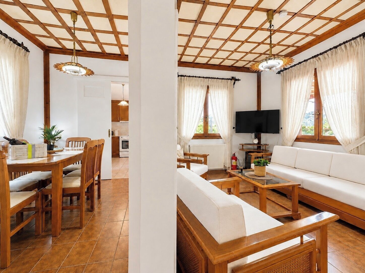 Un salon comprenant un canapé, une table basse et un téléviseur, attenant à une salle à manger avec une table et des chaises.