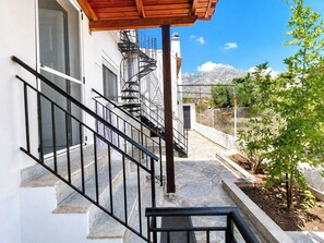 A staircase leading to a white building with a metal railing, a wooden pergola, and a view of mountains. - Kineta Garden Retreat - Coastal House for 8 by ΜΡS (Kineta)
