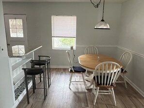 A dining area with a round table, white chairs, a pendant light, and a window with blinds. - Family & pet friendly 3 BDR, walk to restaurants & nightlife in Murray Hill (Jacksonville)