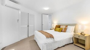 Une chambre à coucher avec un lit, des tables de chevet et une armoire.