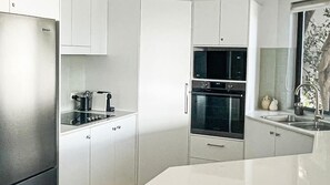 A modern kitchen with stainless steel appliances, white cabinetry, and a double oven. - Belmore Palms Sunshine Beach (Sunshine Beach)