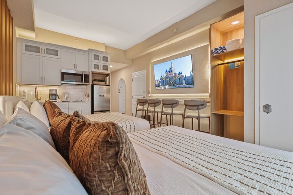 Une chambre d’hôtel comprenant un lit, une kitchenette, une télévision et une salle de bain.