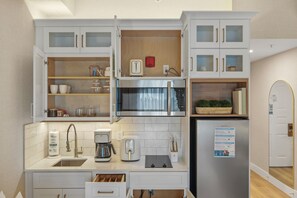 Une cuisine compacte équipée d’un four à micro-ondes, d’un grille-pain, d’une machine à café et d’un réfrigérateur.