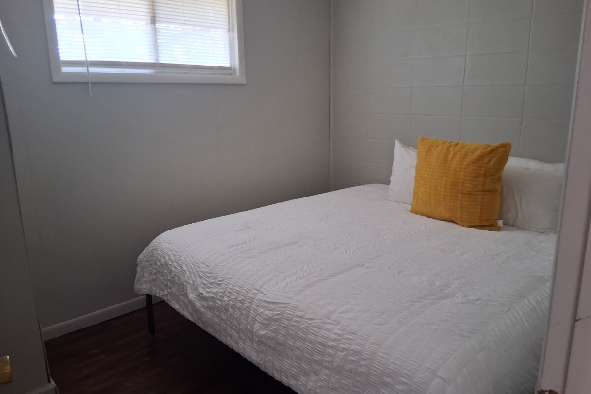 A bedroom with a bed, a window, and a door.