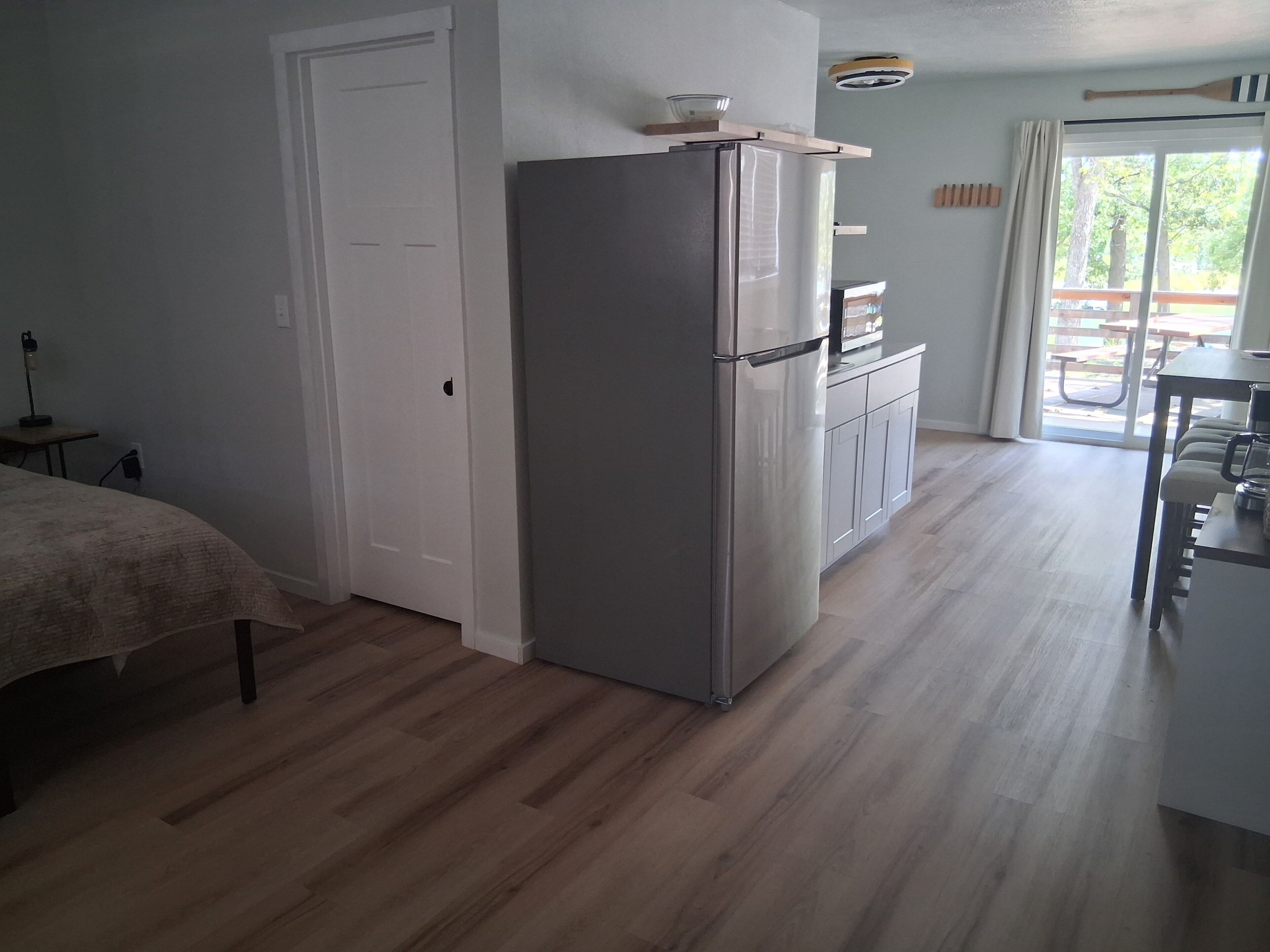 A modern kitchen with a refrigerator, a dining table, and a bench.