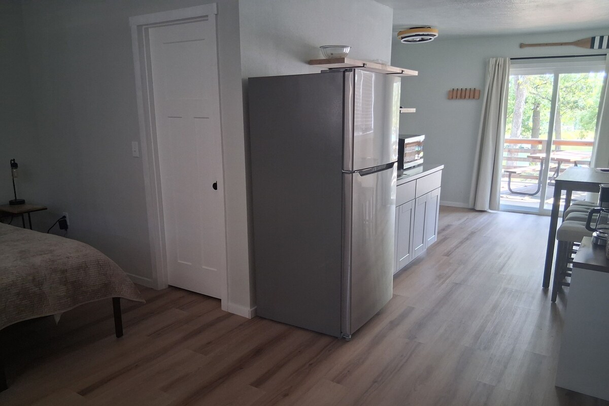 A modern kitchen with a refrigerator, a dining table, and a bench.