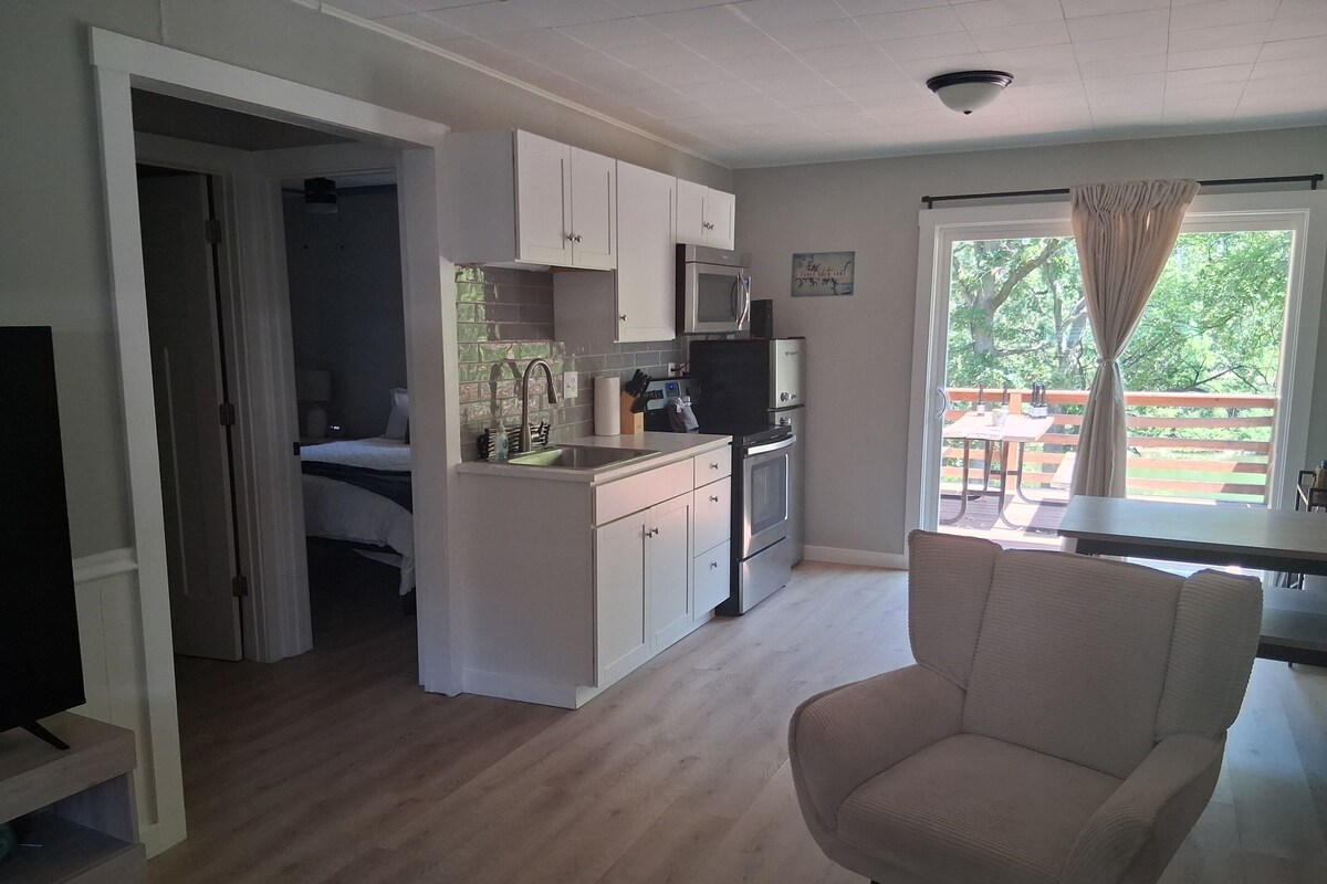 A compact living space with a kitchenette, a dining area, and a bedroom.