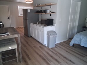 A compact kitchen with a refrigerator, microwave, and wooden shelves. - Kimberling Cove Resort (Kimberling City)