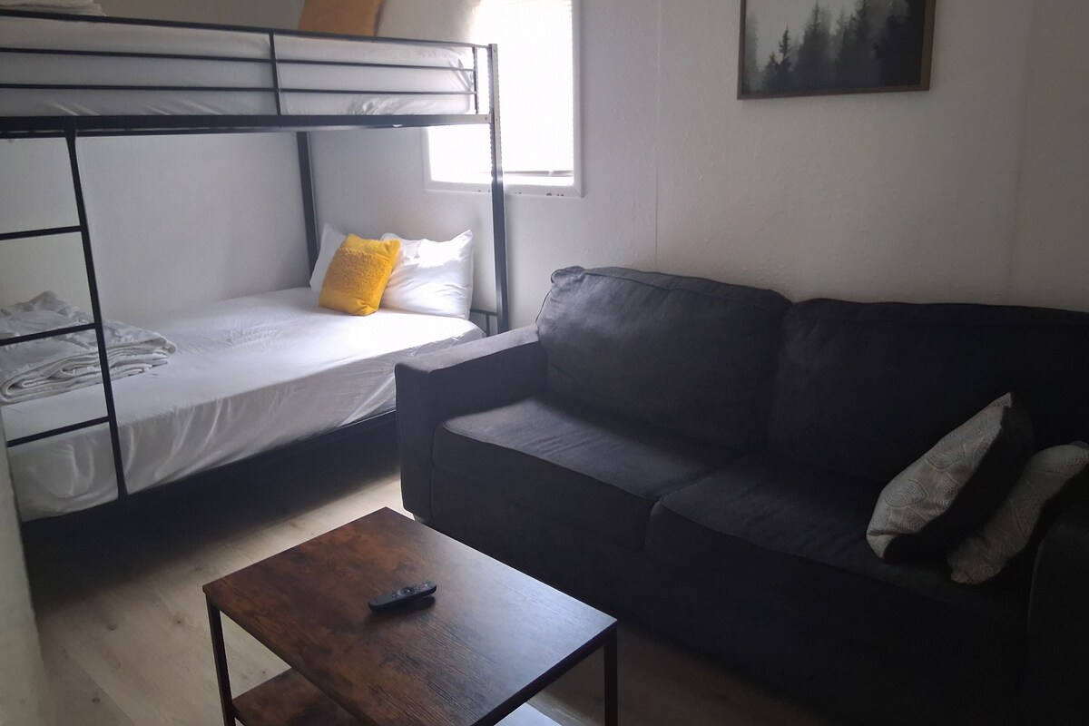 A room with a bunk bed, a sofa, and a small table.